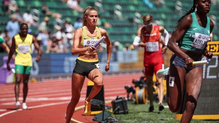 Alica Schmidt läuft mit einem Staffelstab in der Hand.