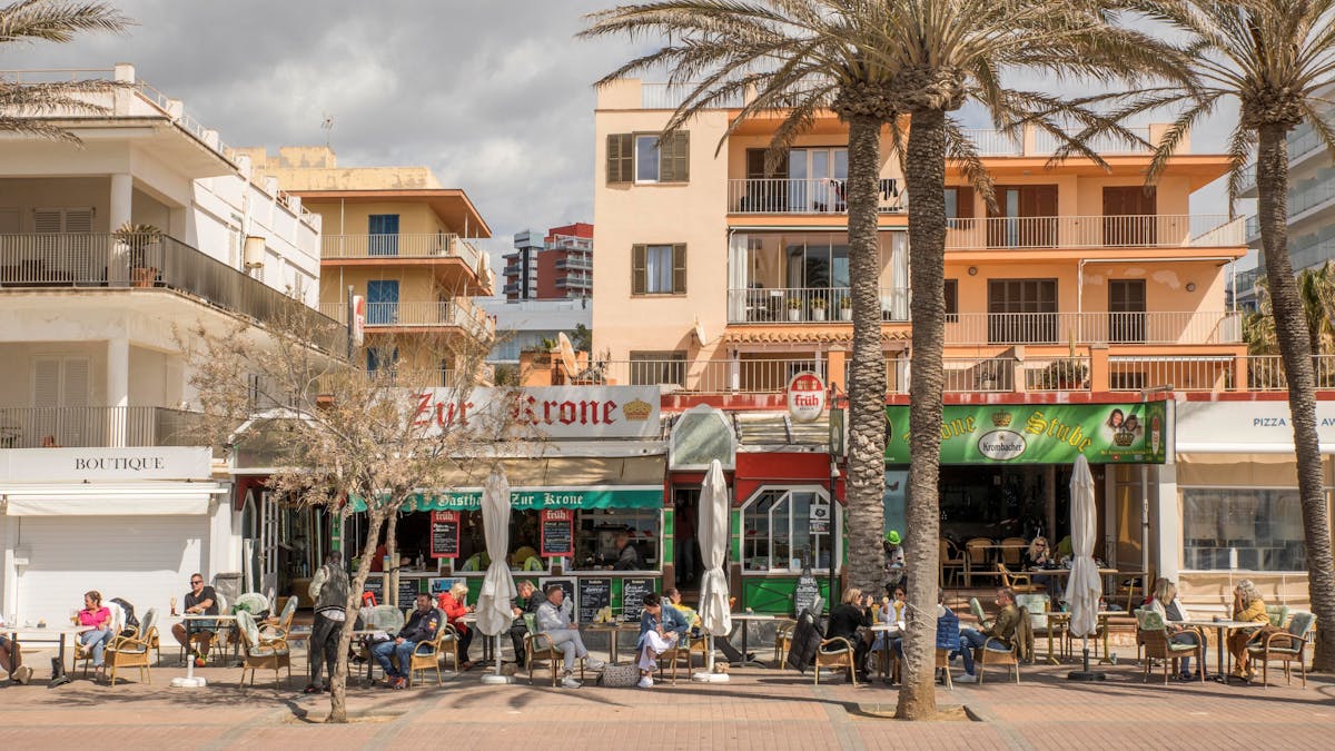 Deutsche Touristen sitzen in der bekannten Bar Zur Krone &amp; Krone Stube und genießen einen Drink in der Sonne an der Playa de Palma auf Mallorca.