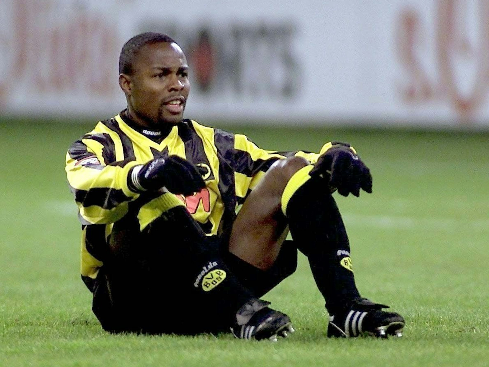 Victor Ikpeba sitzt im Dortmund-Trikot auf dem Boden.