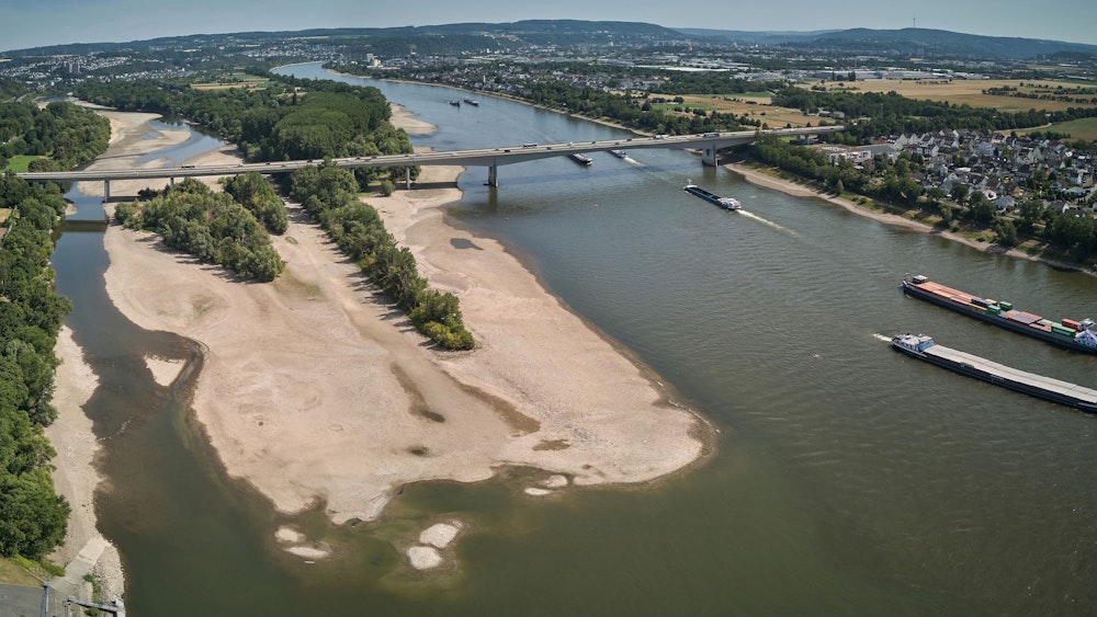 In der anhaltenden Trockenheit des Hochsommers fällt der Wasserspiegel des Mittelrheins immer weiter. Die Luftaufnahme zeigt Frachtschiffe, die bei Bendorf am Rhein eine Sandbank passieren.