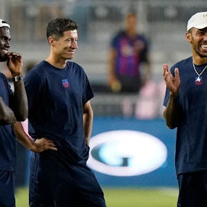 Robert Lewandowski steht im T-Shirt des FC Barcelona neben Franck Kessie, der eine Kappe trägt.
