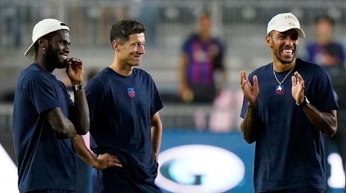 Robert Lewandowski steht im T-Shirt des FC Barcelona neben Franck Kessie, der eine Kappe trägt.