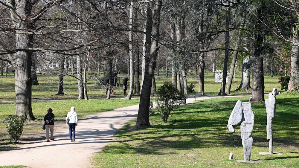 Skulpturen stehen und Fußgänger gehen am 24. März 2022 im Schlosspark in Köln-Stammheim spazieren.