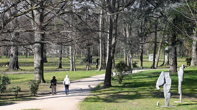 Skulpturen stehen und Fußgänger gehen am 24. März 2022 im Schlosspark in Köln-Stammheim spazieren.