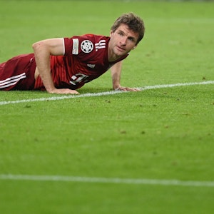 Thomas Müller stützt sich mit beiden Händen auf dem Rasen ab.