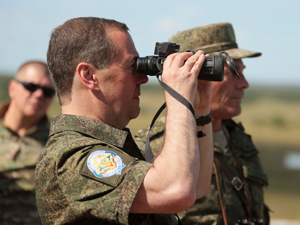 Deputy head of Russia's Security Council and chairman of the United Russia party, Dmitry Medvedev looks through a binocular as he visits Totsk military garrison in the Orenburg region, Russia, Friday, Aug. 5, 2022. (Ekaterina Shtukina, Sputnik, Pool Photo via AP)