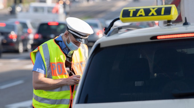 Ein Polizist kontrolliert in Darmstadt einen Taxifahrer.