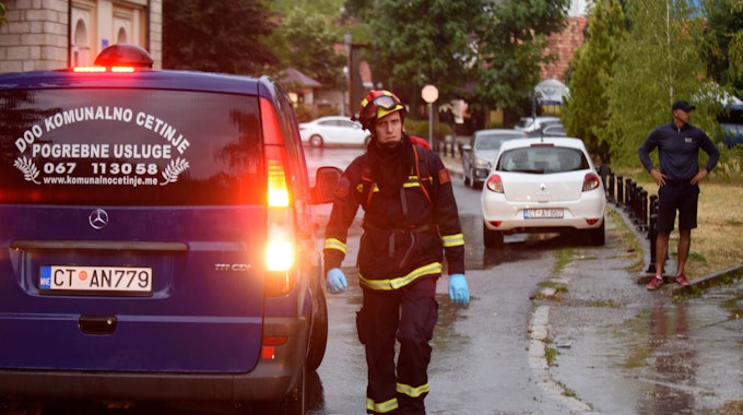 Ein Feuerwehrmann geht an einem Leichenwagen am Ort eines Amoklaufs vorbei. In Montenegro ist ein Mann nach einem Familienstreit Amok gelaufen und hat mehrere Menschen erschossen, bevor er erschossen wurde.