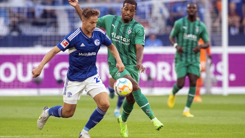 Borussia Mönchengladbach hat am Samstag (13. August 2022) beim FC Schalke 04 2:2 gespielt. Das Foto zeigt Gladbachs Alassane Plea (r.) im Zweikampf mit Schalkes Cédric Brunner (l.).