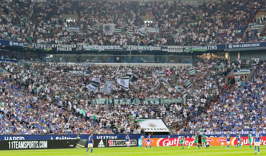 Tausende Fans von Fußball-Bundesligist Borussia Mönchengladbach im Gästeblock der Arena während des Tospiels beim FC Schalke 04 am 13. August 2022. Zu sehen sind Fahnen und Banner.