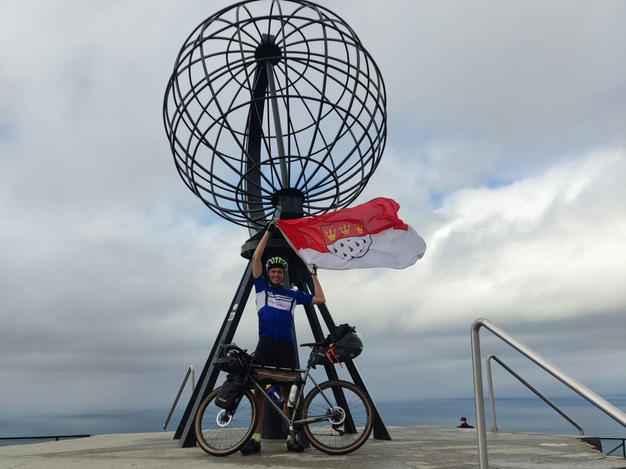 Sebastian mit Rad und Köln-Flagge auf der Spenden-Tour.