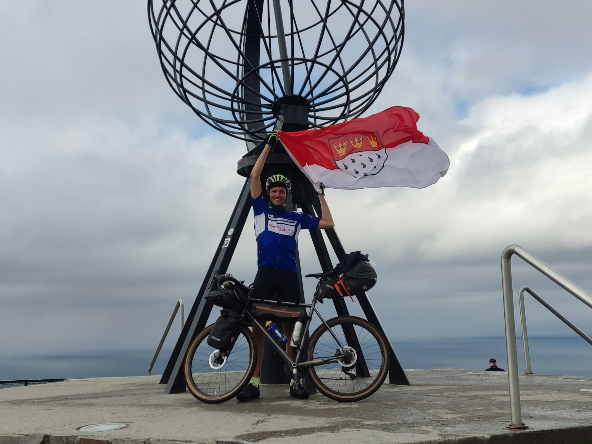 Sebastian Knobloch mit Rad und Köln-Flagge auf der Spenden-Tour