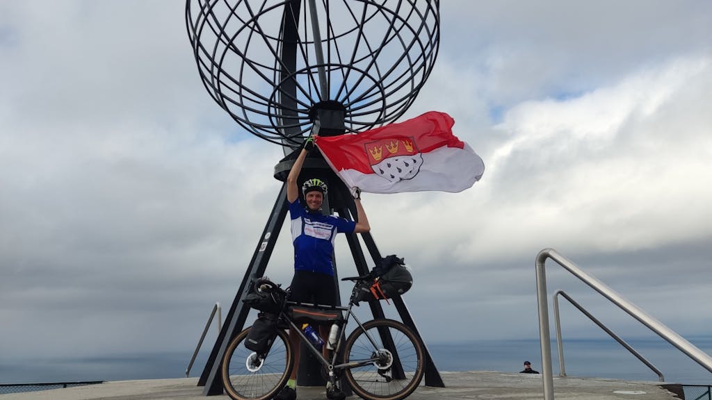Sebastian Knobloch mit Rad und Köln-Flagge auf der Spenden-Tour