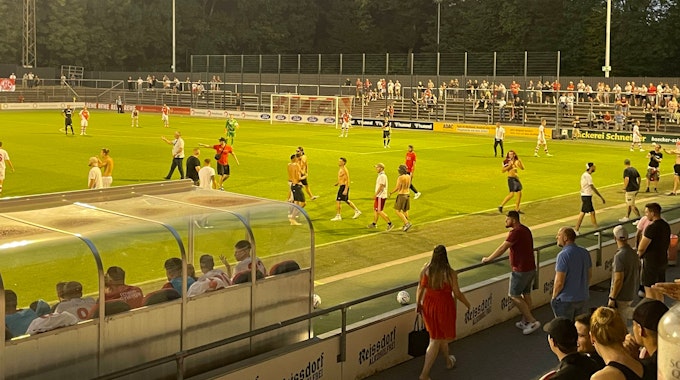 Fans des 1. FC Köln laufen auf den Rasen im Franz-Kremer-Stadion.