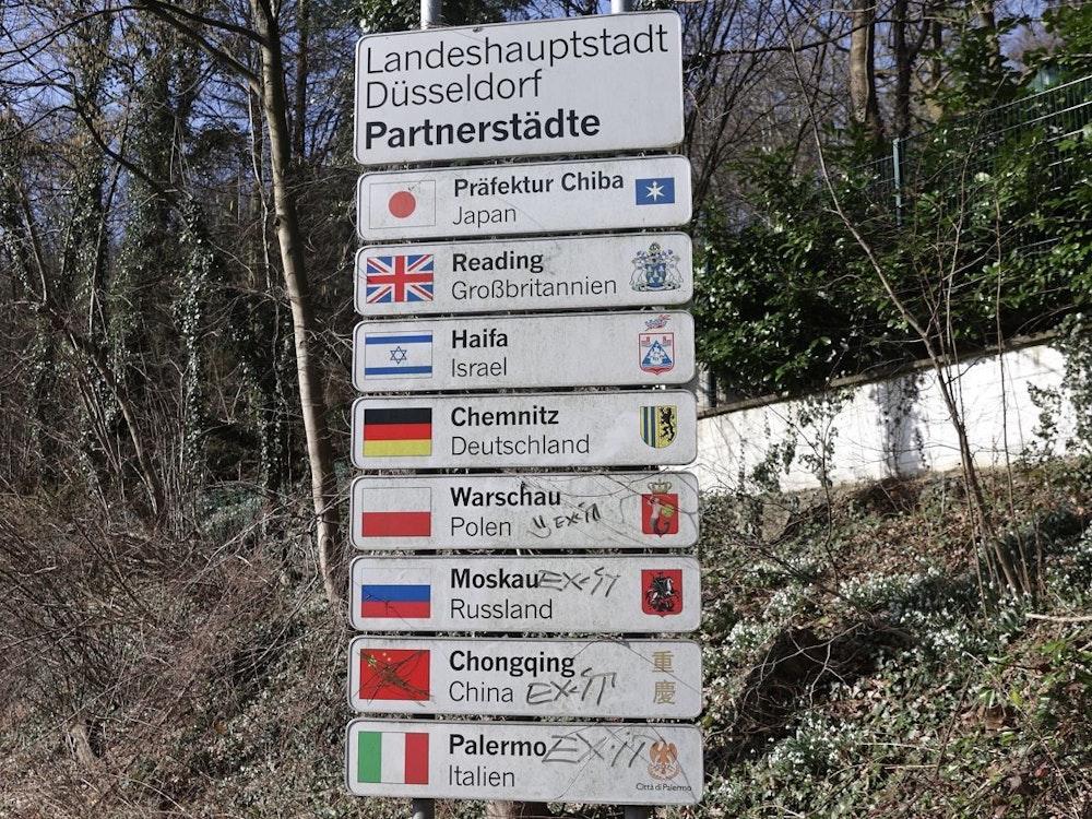 Ein Schild, das Partnerschaften mit anderen Städten anzeigt, steht in Düsseldorf. Auch Moskau ist aufgelistet.