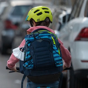 Ein Schulkind fährt mit seinem Fahrrad eine Straße entlang.