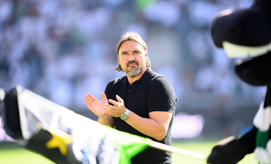 Gladbach-Trainer Daniel Farke. Auf diesem Bild ist der 45-Jährige am 6. August 2022 im Borussia-Park zu sehen. Im Vordergrund schwenkt Borussia-Maskottchen Jünter eine Fahne in den Vereinsfarben.