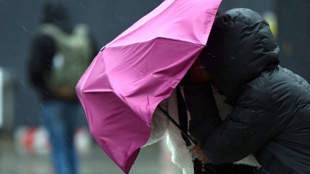 Eine Passantin in Köln kämpft bei Regen und Sturm mit ihrem Regenschirm. Symbolaufnahme von Februar 2022.