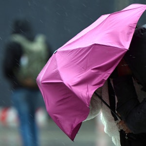 Eine Passantin in Köln kämpft bei Regen und Sturm mit ihrem Regenschirm. Symbolaufnahme von Februar 2022.