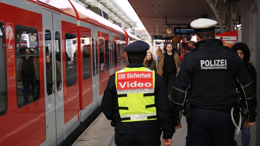 Ein Mitarbeiter des Sicherheitsdienstes der Deutschen Bahn und ein Bundespolizist gehen durch einen Bahnhof.