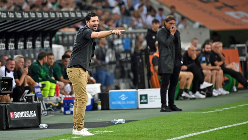 Sandro Schwarz (l.), Trainer von Hertha BSC, am 19. August 2022 im Borussia-Park. Im Hintergrund ist Gladbach-Coach Daniel Farke (r.) zu sehen. Beide Trainer stehen an der Seitenlinie.