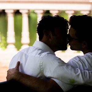 Zwei Männer sitzen zusammen auf einer Parkbank und küssen sich. Es handelt sich um ein undatiertes Symbolbild anlässlich des Tags des Kusses am 6. Juli.