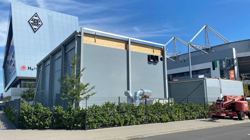 Auf dem Parkplatz P10 im Borussia-Park entsteht der neue Kraftraum für die Profis von Borussia Mönchengladbach. Im Vordergrund steht der Neubau, im Hintergrund sind das Stadion und das H-Hotel zu sehen.