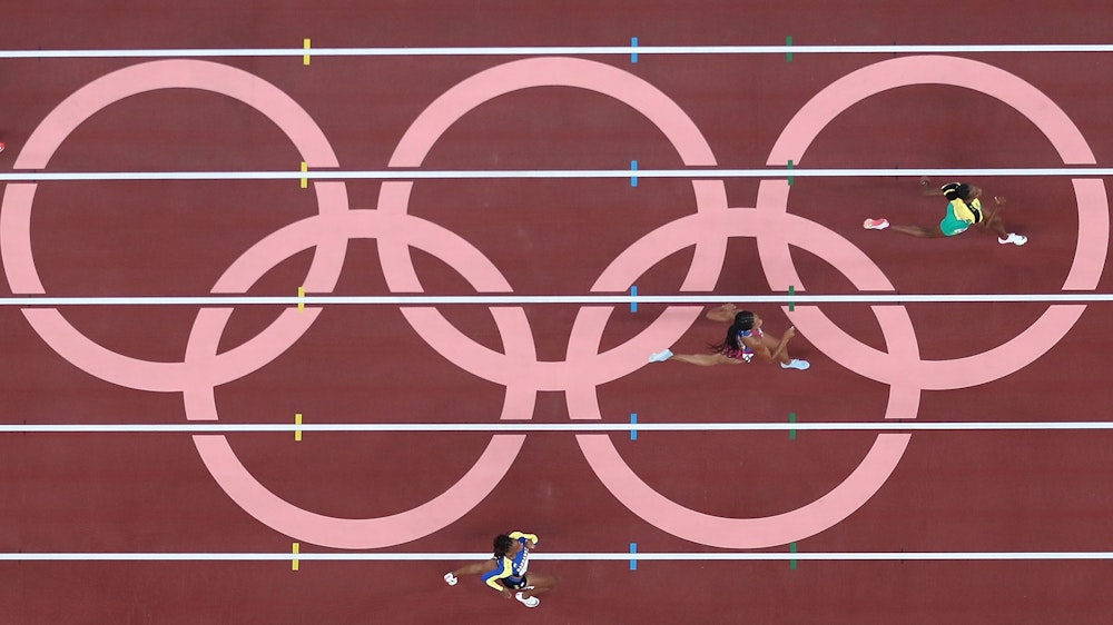 Läuferinnen laufen über die Tartanbahn, die von den olympischen Ringen geziert ist.