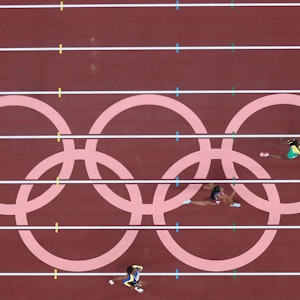 Läuferinnen laufen über die Tartanbahn, die von den olympischen Ringen geziert ist.