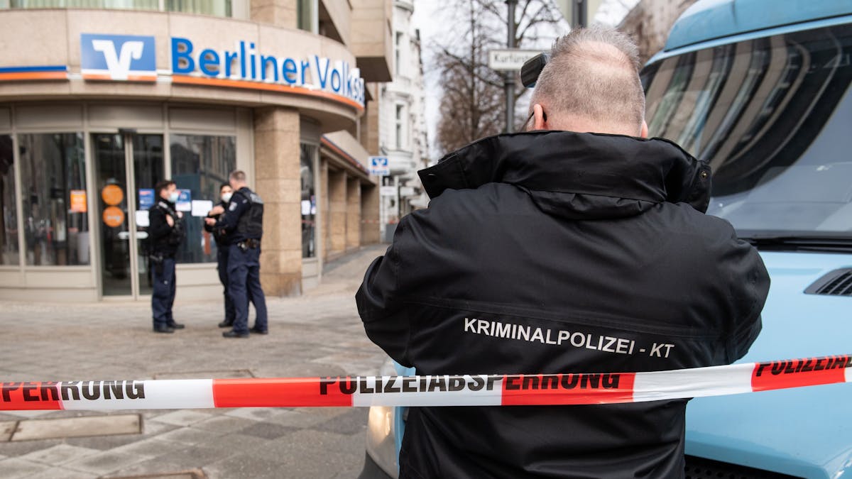 Polizeibeamte in Berlin sichern vor einer Bank an einem Geldtransporter Spuren, nachdem dieser überfallen wurde.