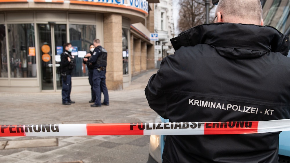 Polizeibeamte in Berlin sichern vor einer Bank an einem Geldtransporter Spuren, nachdem dieser überfallen wurde.