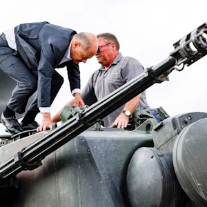 Bundeskanzler Olaf Scholz (l.) klettert mit dem Ausbildungsleiter des Waffenherstellers Krauss-Maffei Jürgen Schoch auf einen deutschen Flakpanzer Gepard