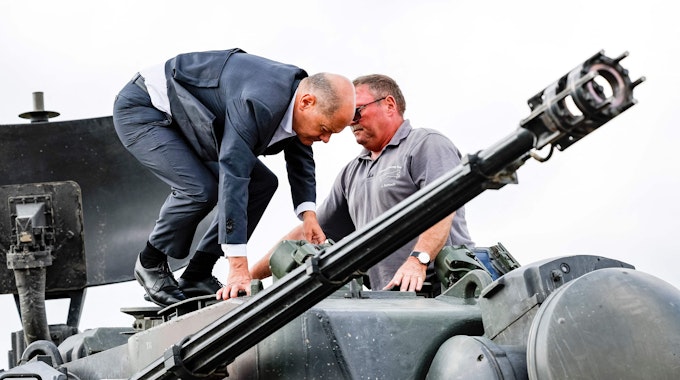 Bundeskanzler Olaf Scholz (l.) klettert mit dem Ausbildungsleiter des Waffenherstellers Krauss-Maffei Jürgen Schoch auf einen deutschen Flakpanzer Gepard