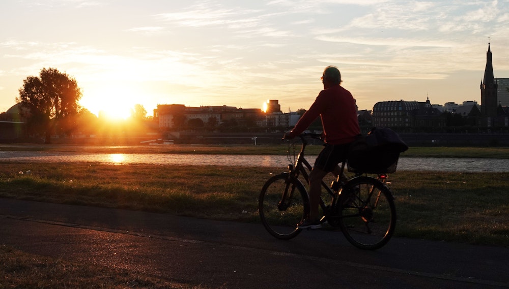 Ein Radfahrer bei Sonnenaufgang am Rheinufer in Düsseldorf. Symbolbild.