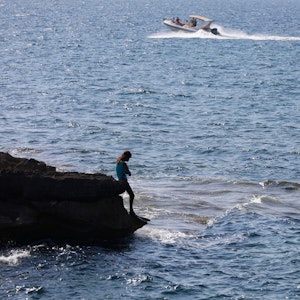 Das Foto von Anfang August 2022 zeigt eine Frau, die auf den Felsen am Strand von Ca los Camps auf Mallorca steht.