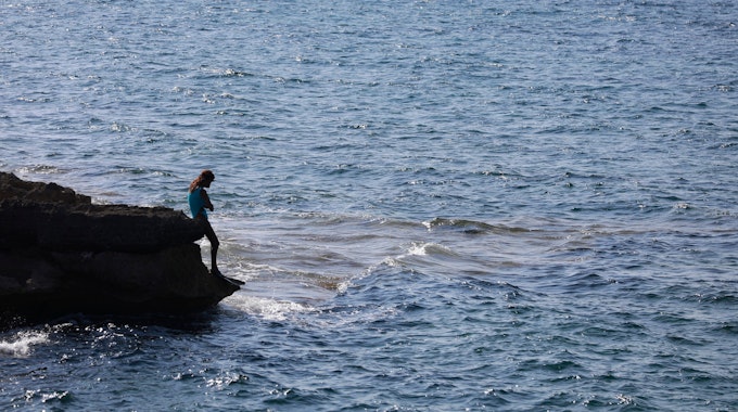 Das Foto von Anfang August 2022 zeigt eine Frau, die auf den Felsen am Strand von Ca los Camps auf Mallorca steht.