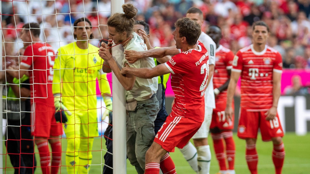 Thomas Müller hindert einen Klima-Aktivisten beim Spiel des FC Bayern gegen Borussia Mönchengladbach daran, sich an einen Torpfosten zu binden.