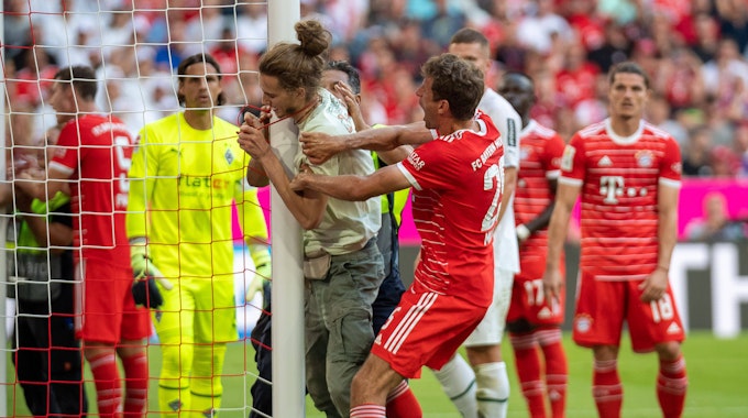 Thomas Müller hindert einen Klima-Aktivisten beim Spiel des FC Bayern gegen Borussia Mönchengladbach daran, sich an einen Torpfosten zu binden.