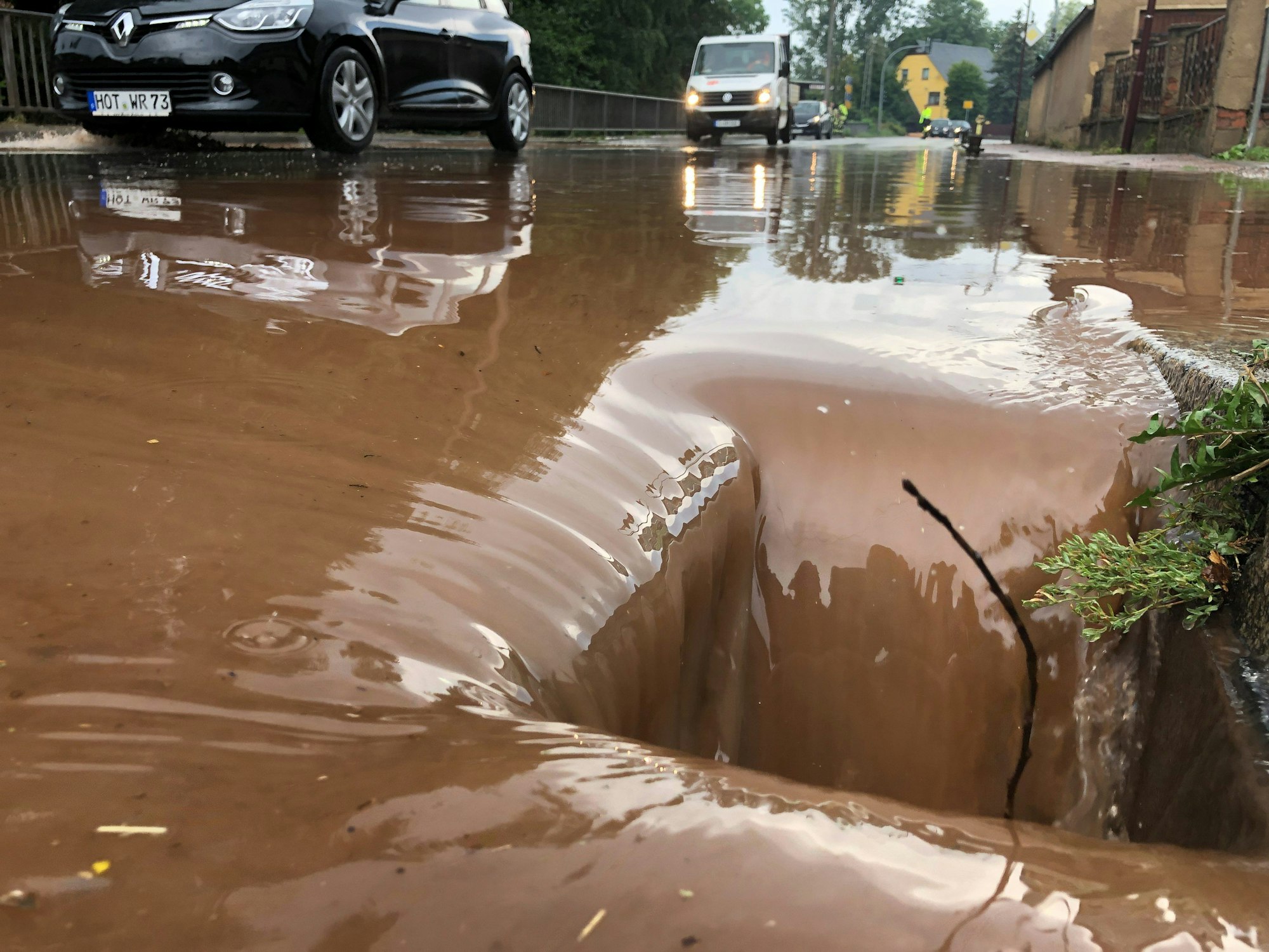 Autos fahren in Oberlungwitz in Sachsen über eine geflutete Straße