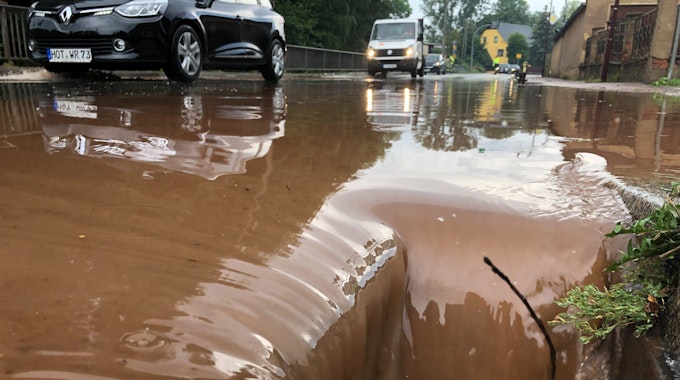 Autos fahren in Oberlungwitz in Sachsen über eine geflutete Straße