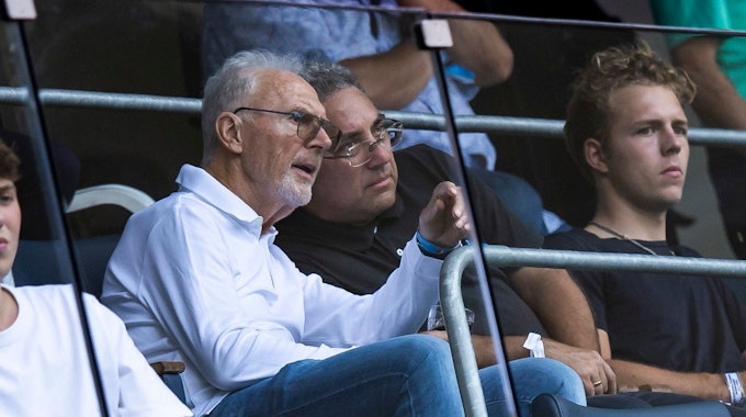 Franz Beckenbauer spricht beim Bundesliga-Spiel der TSG Hoffenheim auf der Tribüne mit seinem Nebenmann