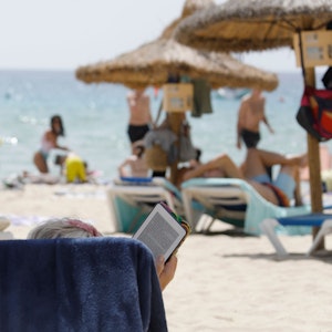 Eine Frau liegt auf einer Sonneliege am Strand von Mallorca