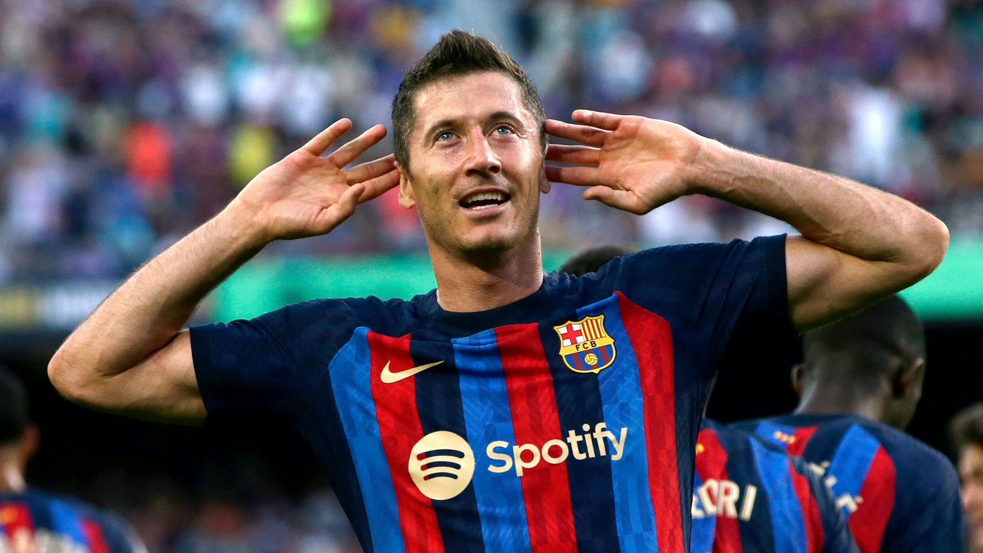Robert Lewandowski vom FC Barcelona jubelt und hält dabei die Hände an seine Ohren, um den Jubel der Zuschauerinnen und Zuschauer zu hören.