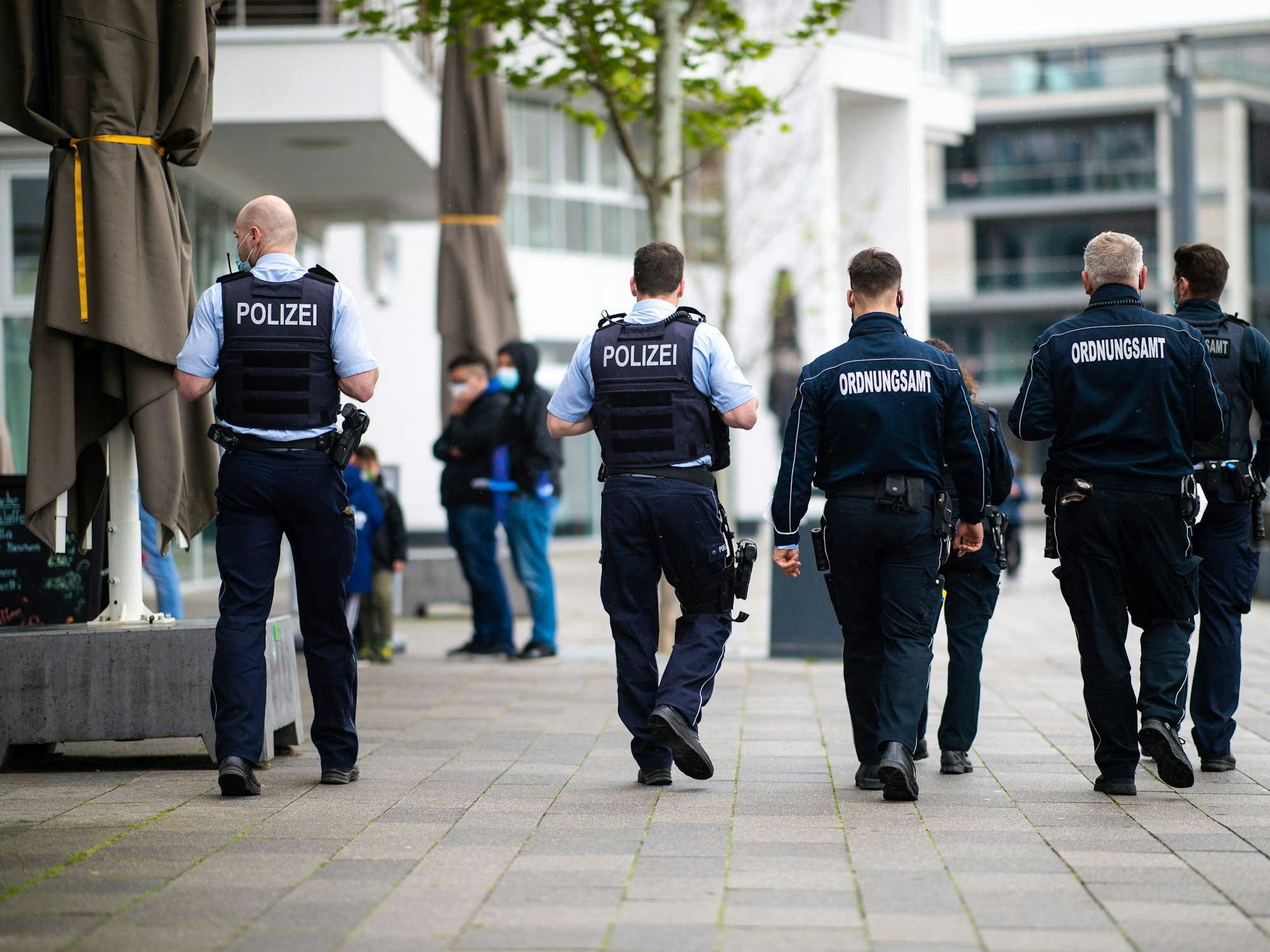 Mitarbeiter des Ordnungsamtes und Polizisten gehen in Dortmund an einer Promenade entlang.