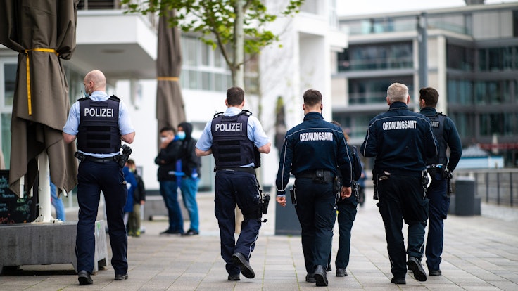 Mitarbeiter des Ordnungsamtes und Polizisten gehen in Dortmund an einer Promenade entlang.