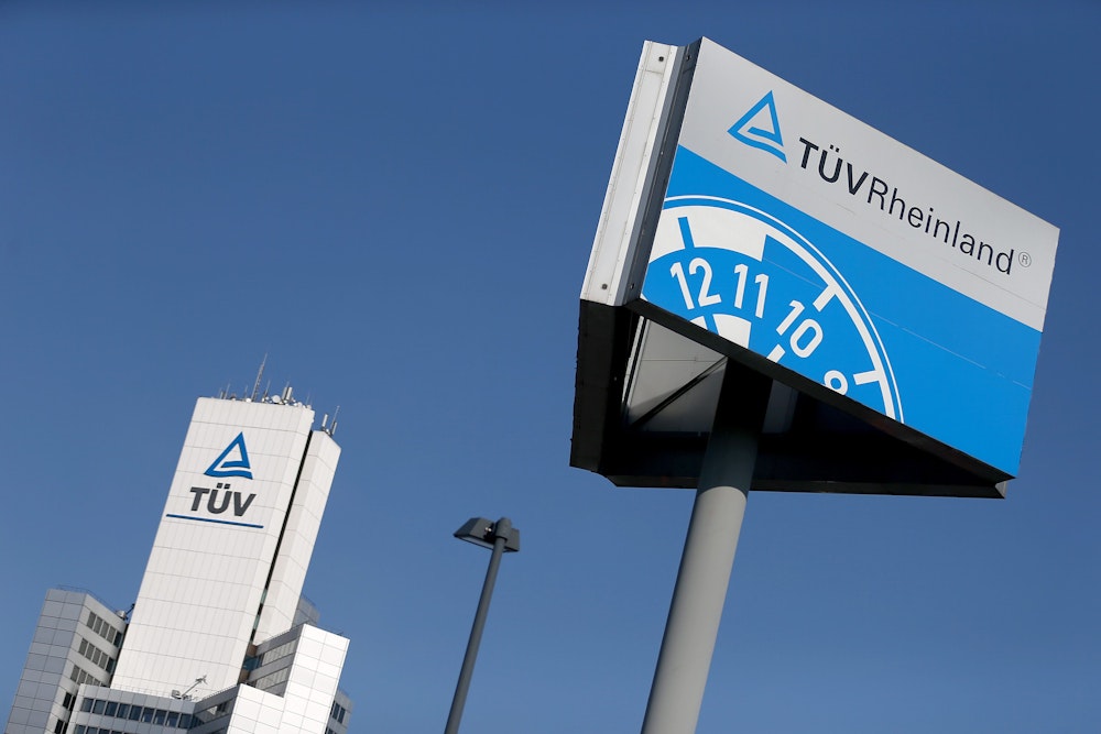 Ein Hinweisschild einer Kfz-Prüfstelle des TÜV Rheinland steht neben der Unternehmenszentrale.