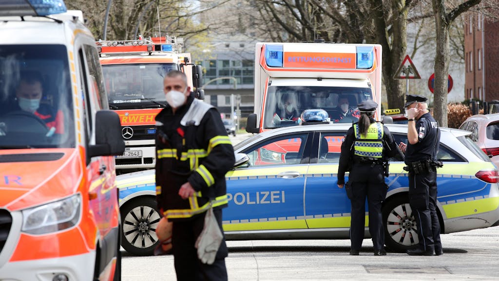 Einsatzkräfte von Polizei und Feuerwehr stehen bei einem Einsatz in Hamburg auf einer gesperrten Straße.&nbsp;
