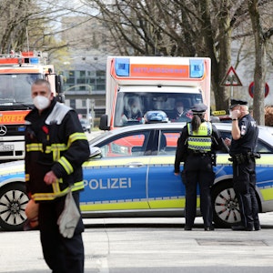 Einsatzkräfte von Polizei und Feuerwehr stehen bei einem Einsatz in Hamburg auf einer gesperrten Straße.