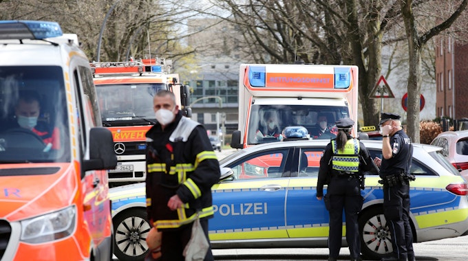 Einsatzkräfte von Polizei und Feuerwehr stehen bei einem Einsatz in Hamburg auf einer gesperrten Straße.