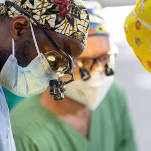 Drei Chirurgen beugen sich über einen Patienten.